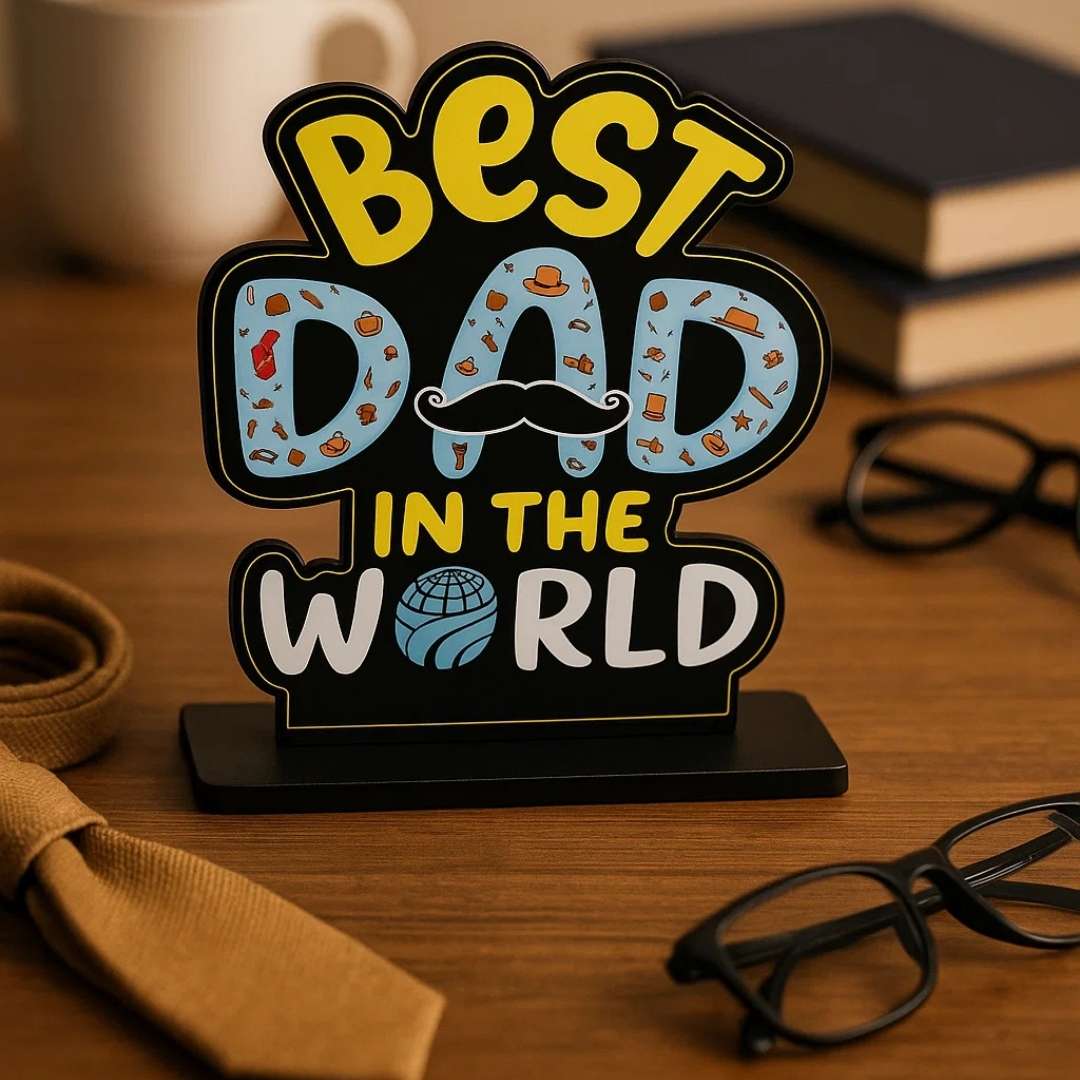 Decorative sign with 'Best Dad in the World' on a wooden surface with books and glasses.