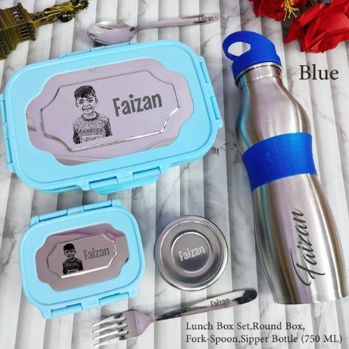 Lunch box set with round box, fork, spoon, and blue-sleeve sipper bottle on a marble surface.
