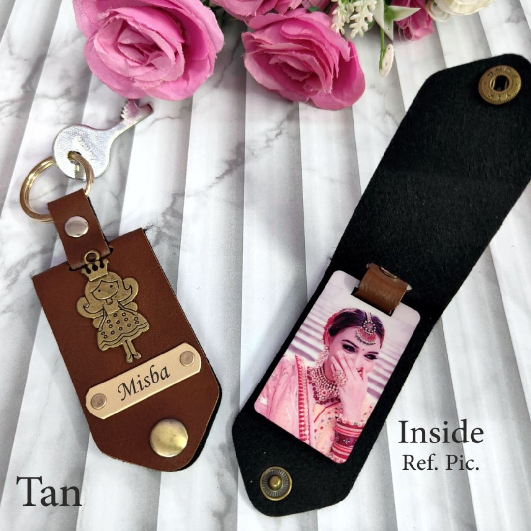 Two Dodge brand keychains, one with a brown background and the other with a black background, both featuring a gold-toned Dodge logo and a photo of a woman on the black keychain with the text 'MISA' and 'INSIDE'.