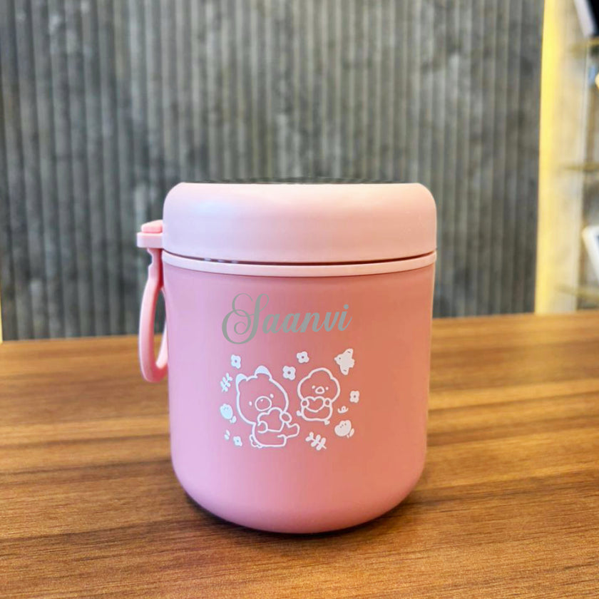 Pink container with 'Jaanvi' branding on a wooden surface