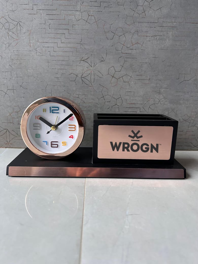 Small clock and black rectangular box with 'WROGN' branding on a gray surface.
