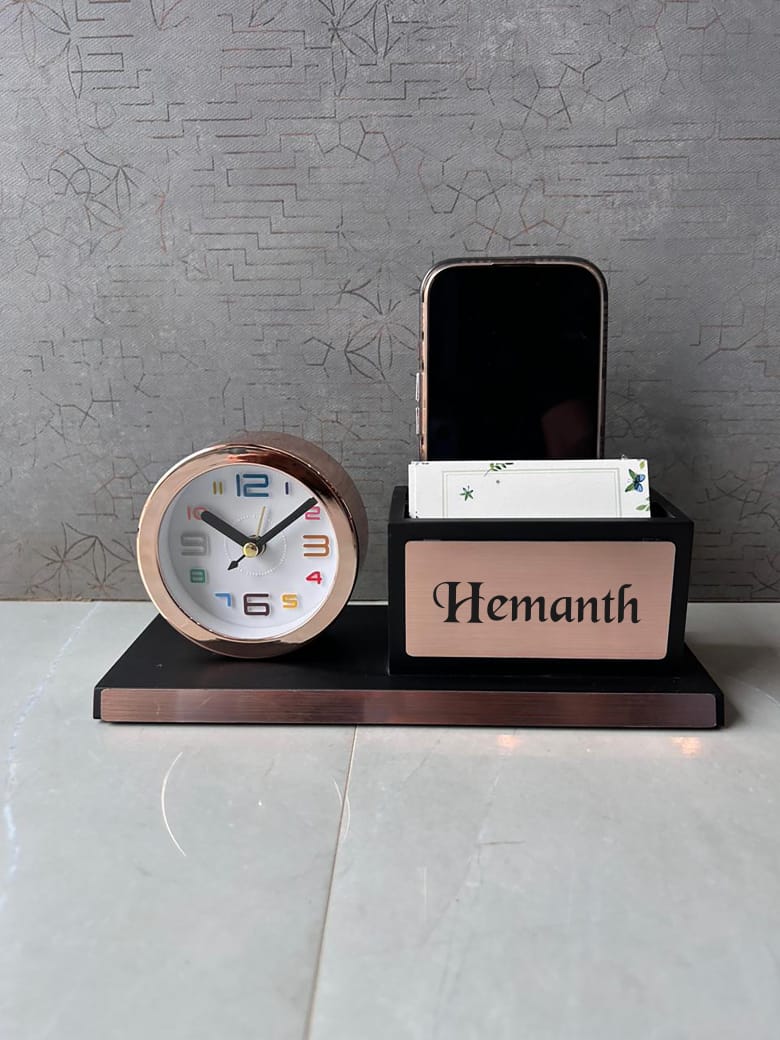 Desk setup with a clock, phone stand, and nameplate on a gray surface.