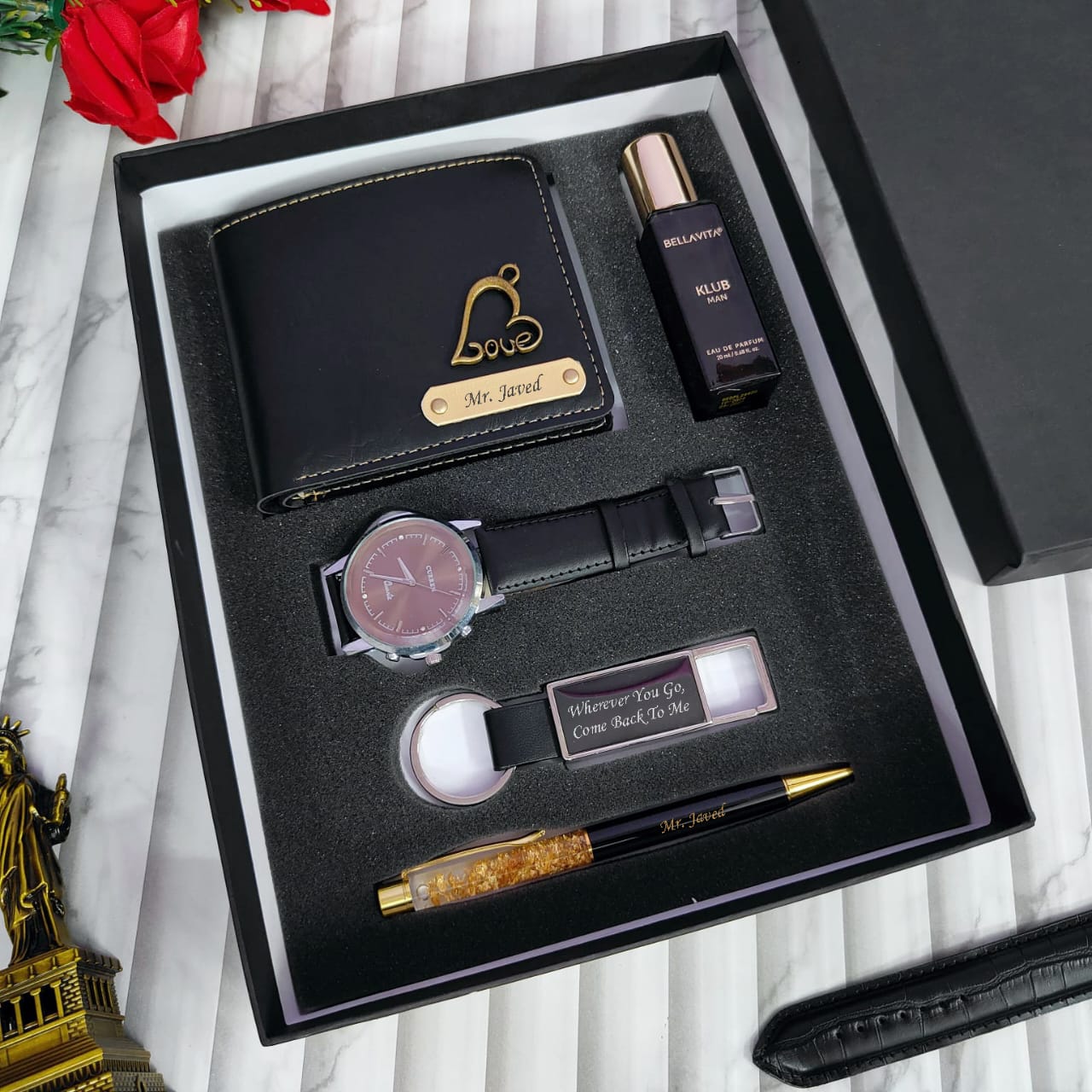 Set of men's accessories including a wallet, watch, pen, and other items in a black box.