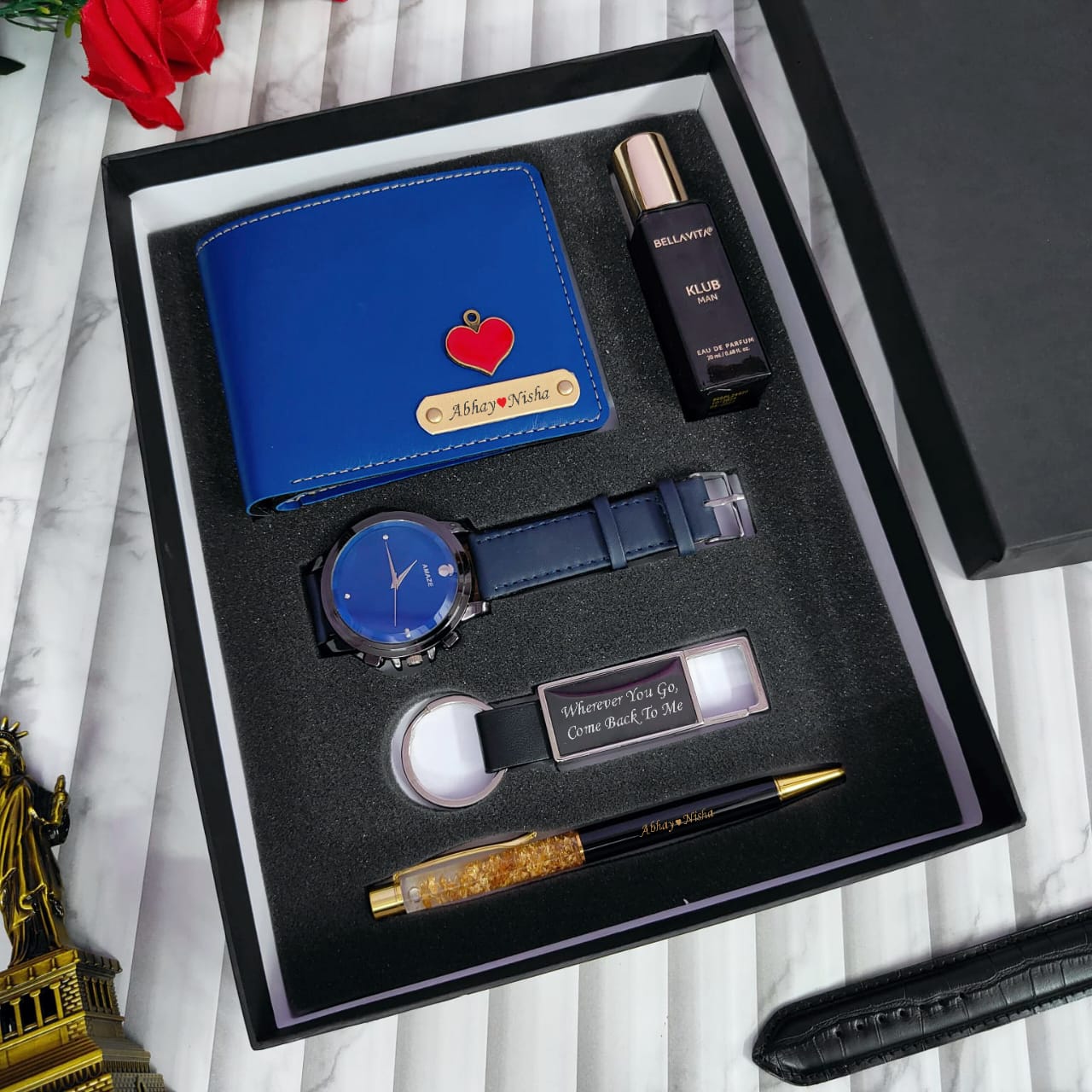 Gift set with blue wallet, watch, pen, and other items in a black box.