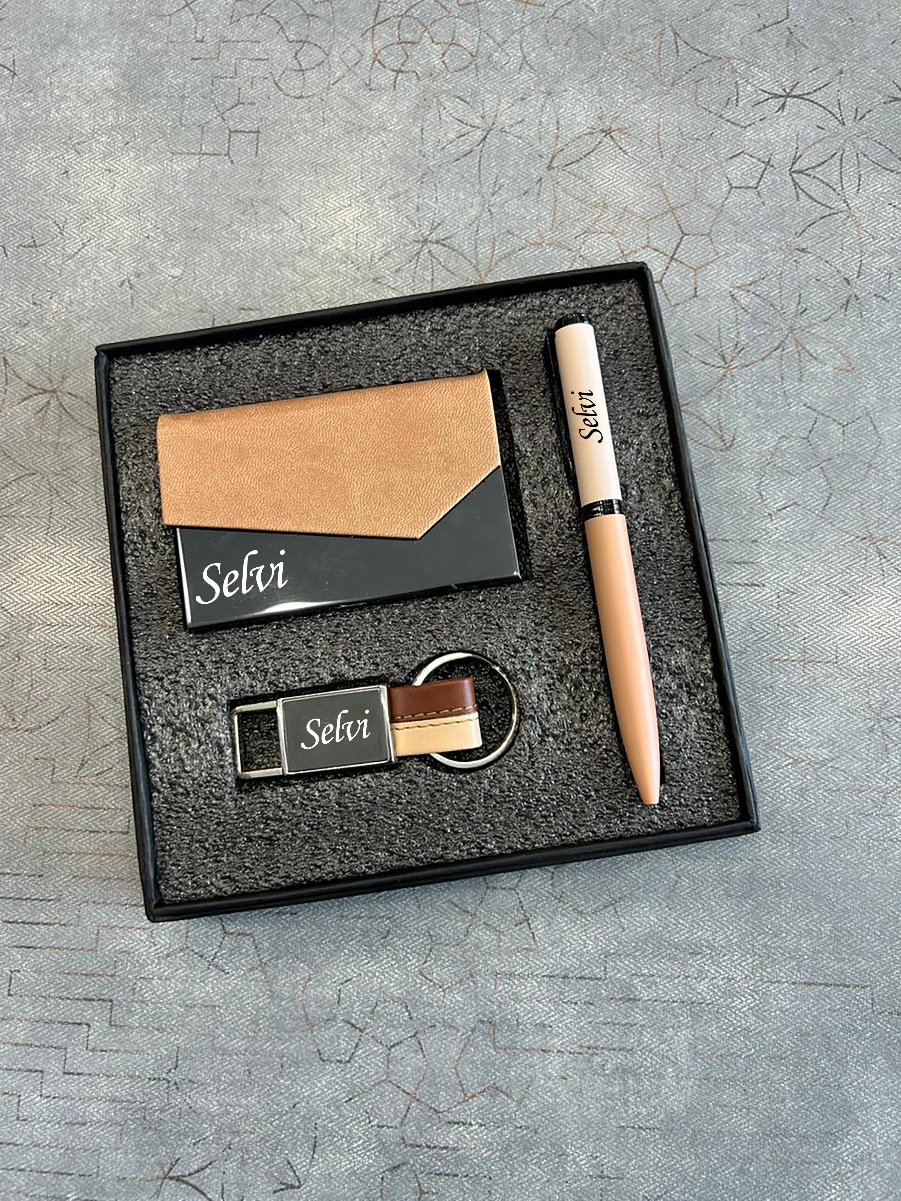 Set of branded items including a card, pen, keychain, and USB drive in a box on a textured gray surface.