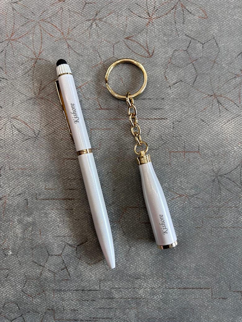 White pen and keychain set on a textured gray surface
