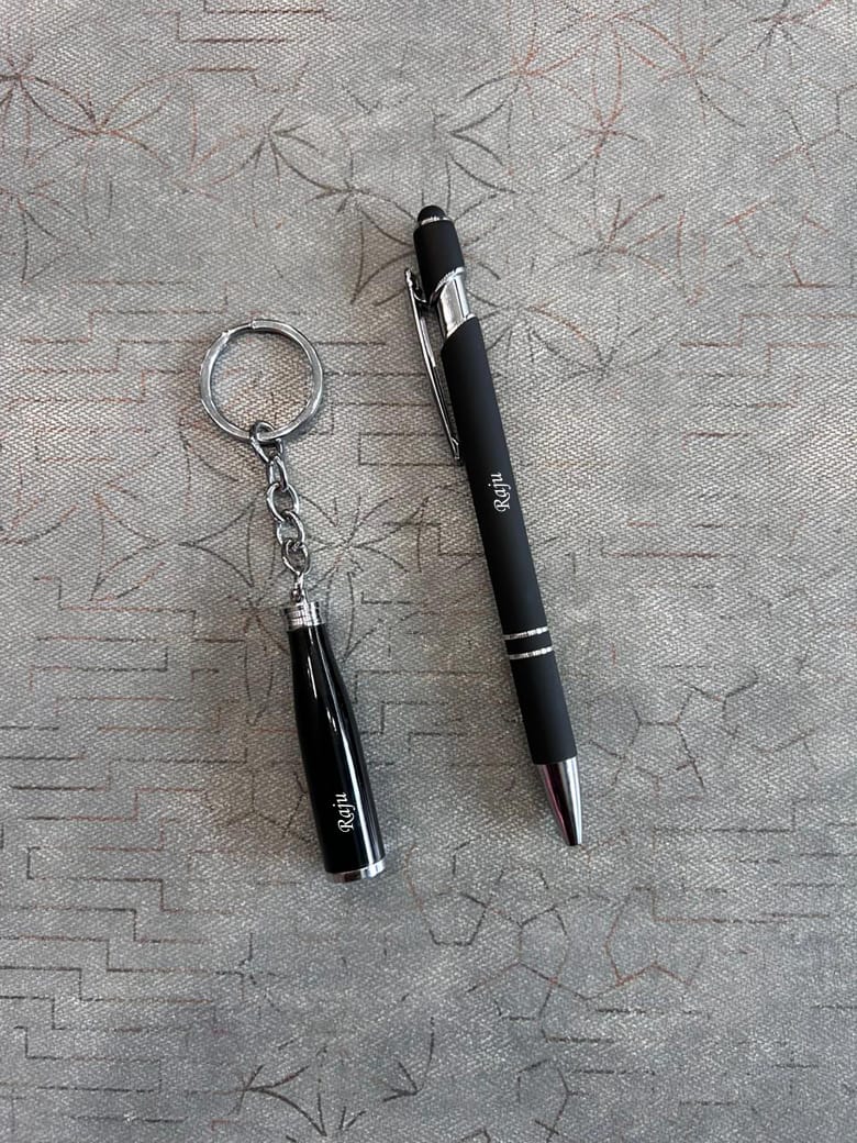Black pen and keychain on a textured gray surface