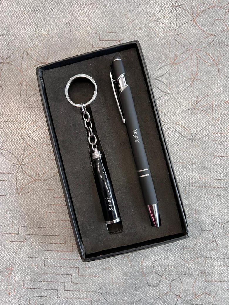 Black pen and keychain set in a box on a textured surface