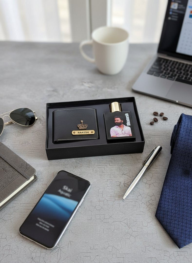 Groomsmen gift set with black box, phone, coffee, and tie on a desk.