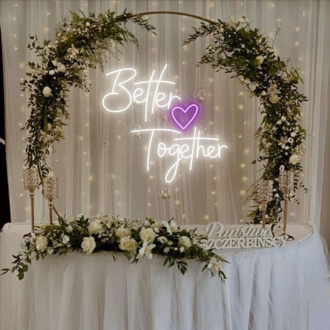 Neon sign reading 'Better Together' with floral arches on a decorated table.
