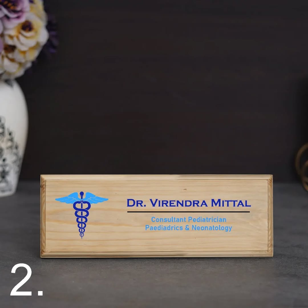 Wooden nameplate with engraved text and logo on a dark surface
