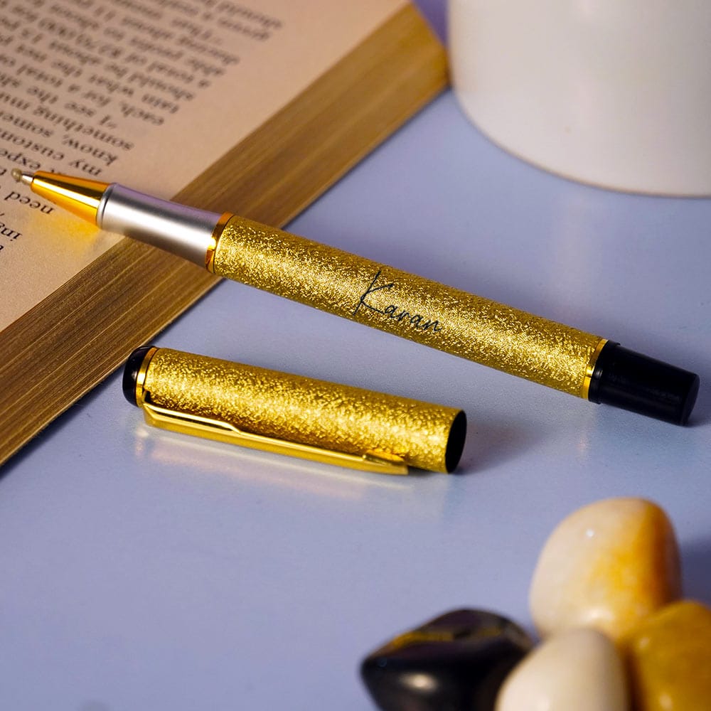 Gold glitter pen on a book with a blurred background