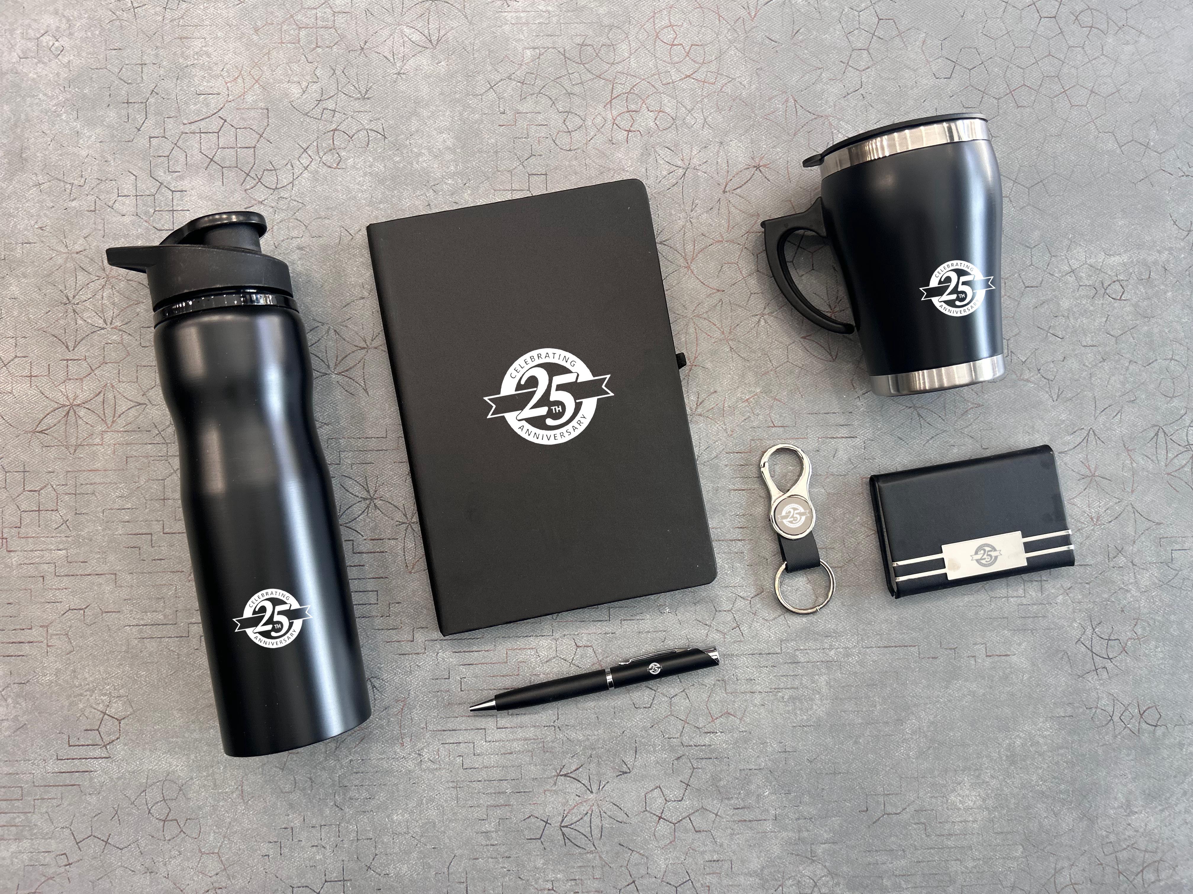 Black branded water bottle, mug, notebook, pen, keychain, and cardholder on a gray surface.