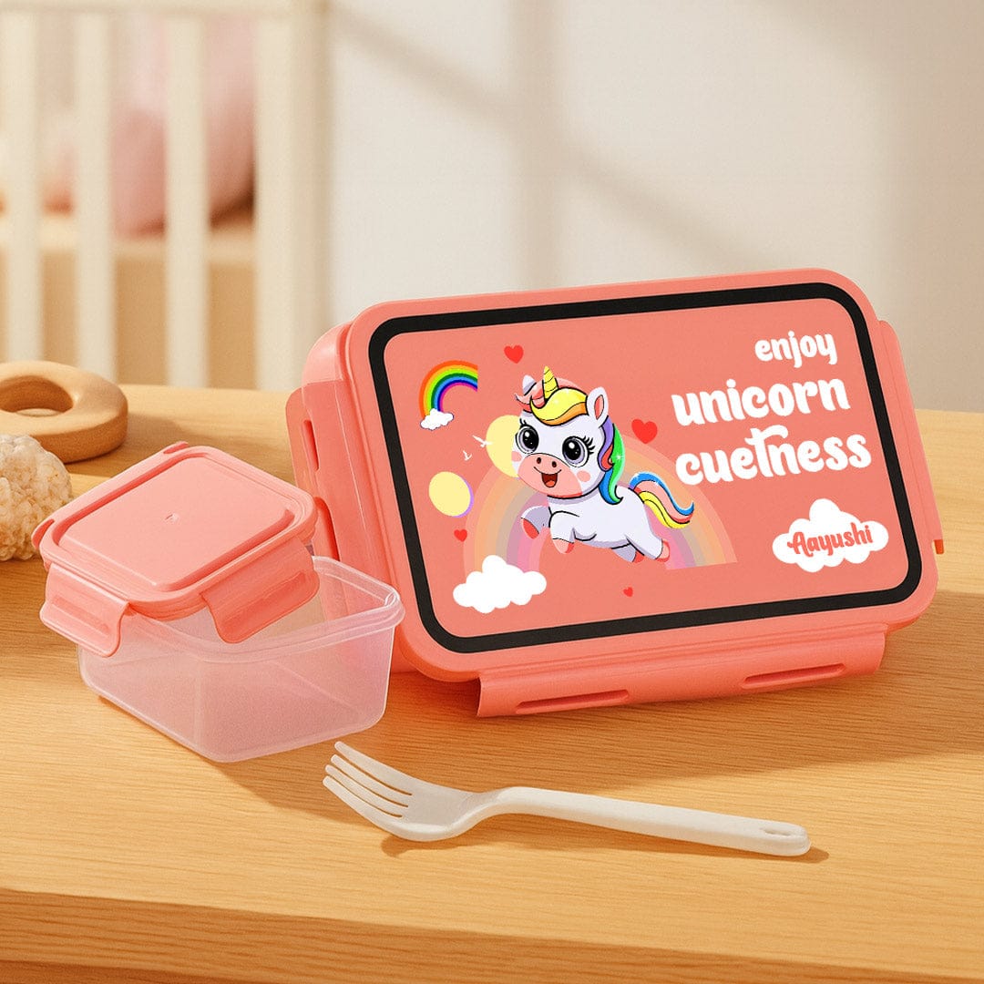 Pink lunch box with unicorn design on a wooden surface