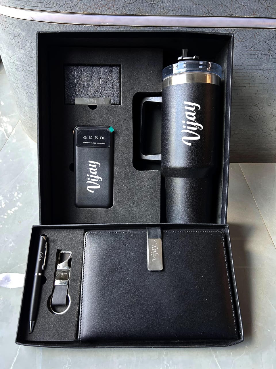 Black gift set with mug, pen, and keychain in a box, featuring the name 'Vijay'.