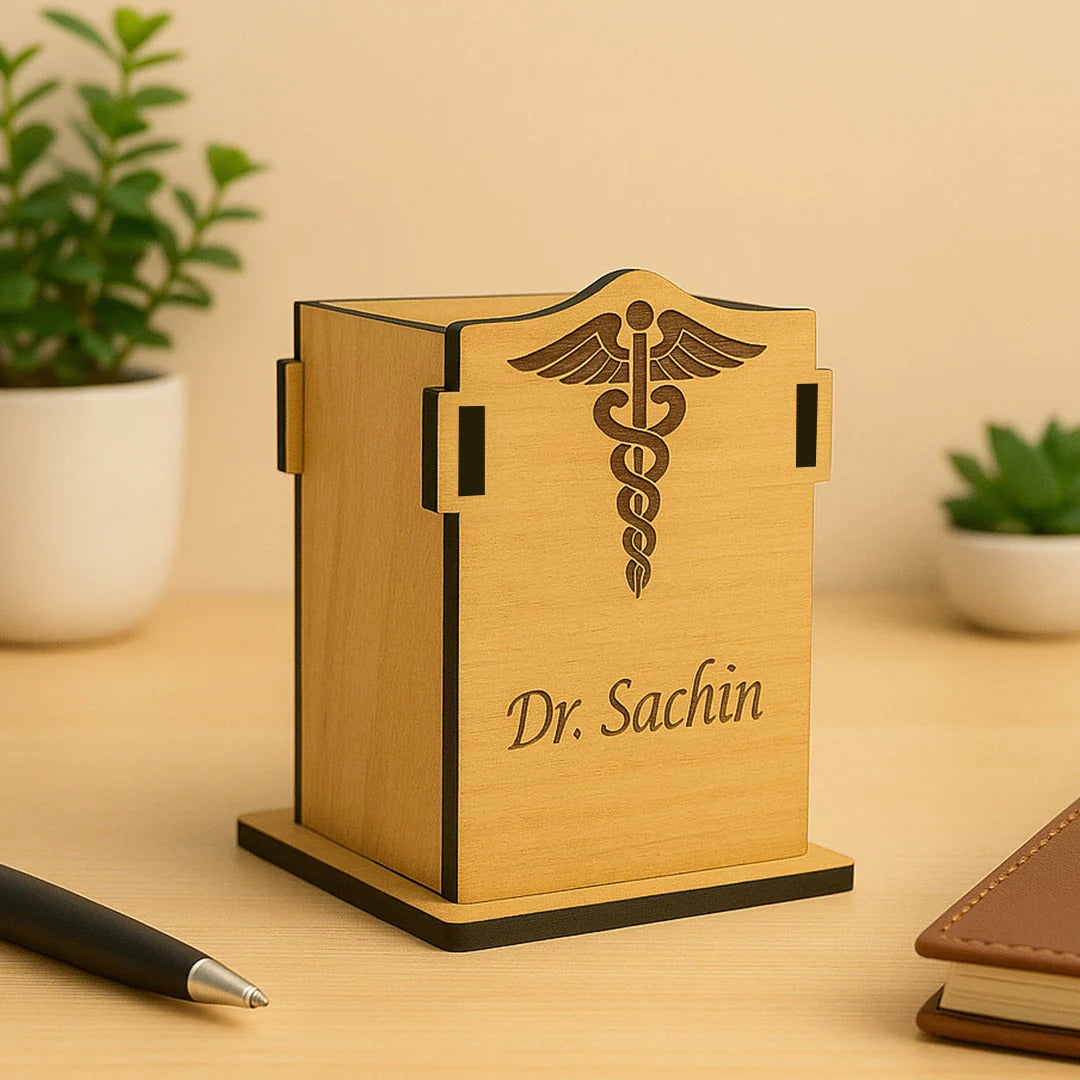 Wooden pen holder with 'Dr. Sachin' engraving on a wooden surface with plants in the background.