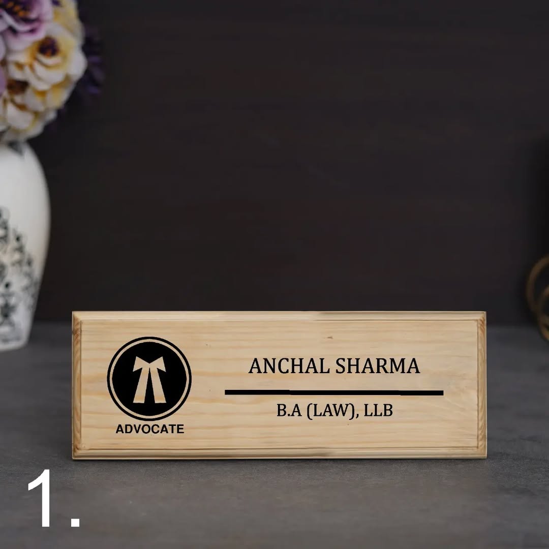 Wooden nameplate with engraved text and logo on a dark surface