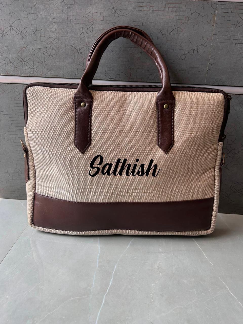 Beige bag with brown handles and trim, featuring the name 'Sathish' on a gray background