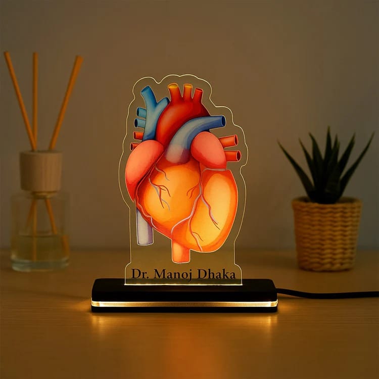 Heart-shaped lamp with 'Dr. Manoj Dhaka' branding on a wooden surface.