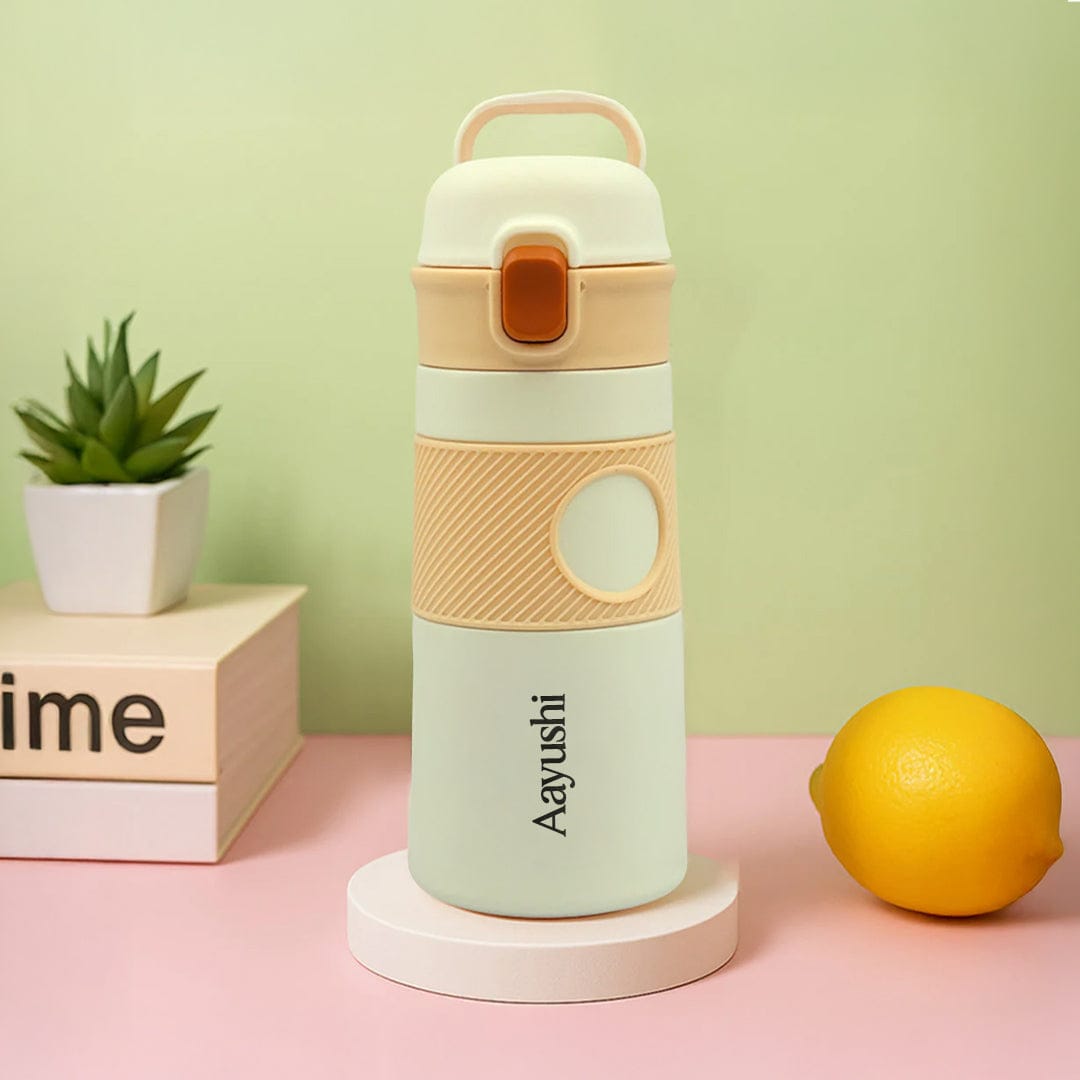 Colorful water bottle with 'Aayushi' branding on a pink surface with a lemon and plant in the background.