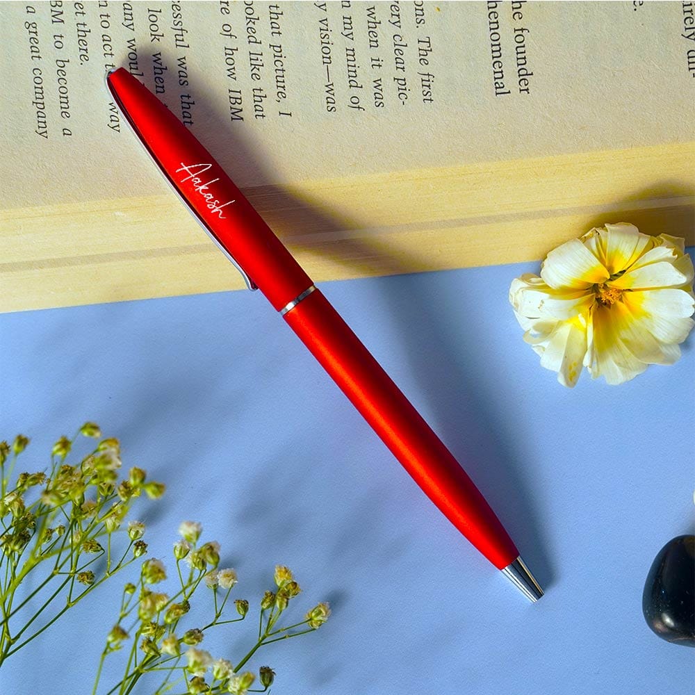 Red pen with 'Adore' branding on a book with flowers