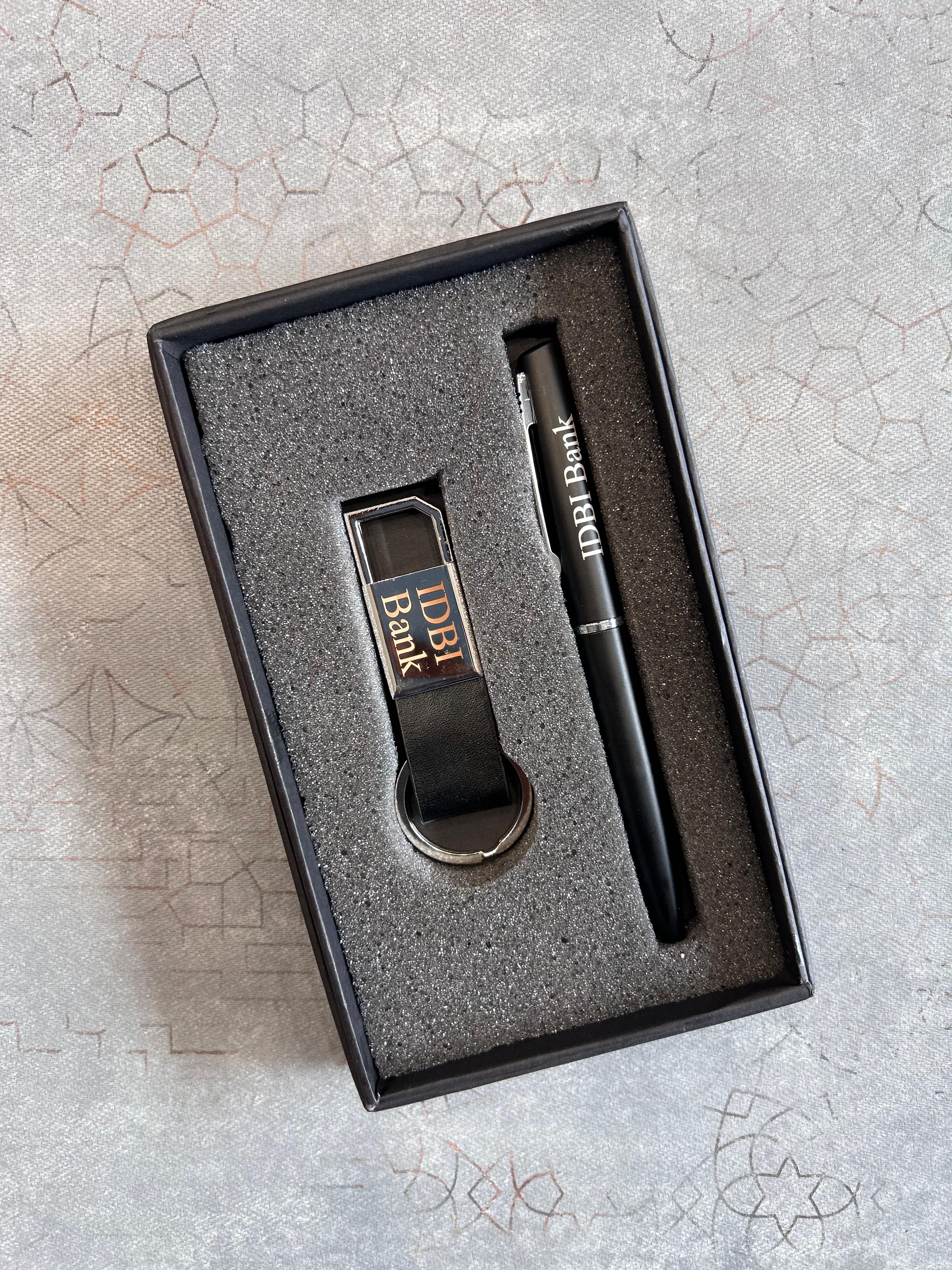 Set of USB drive and pen with 'IDBI Bank' branding in a box on a textured surface