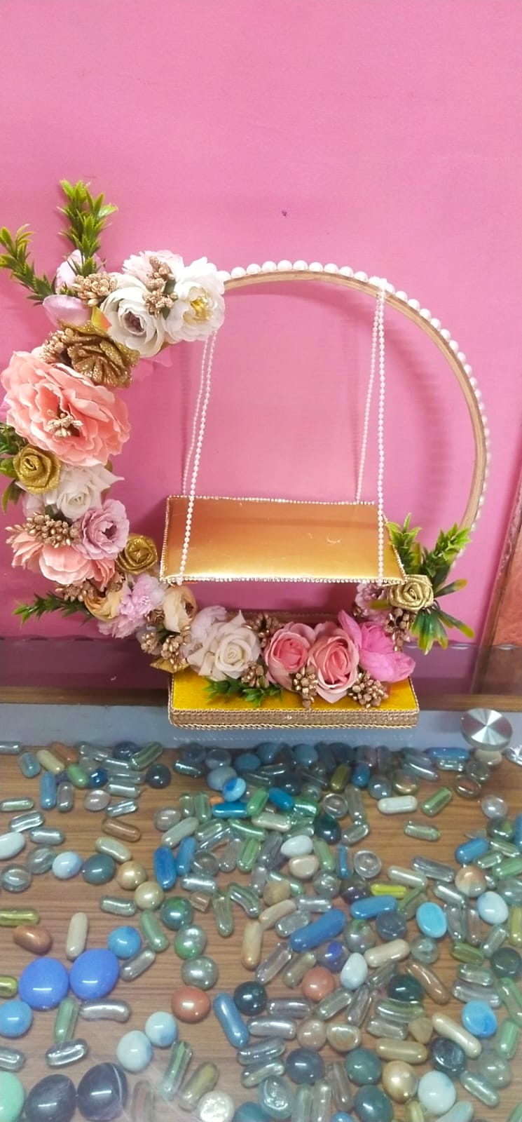 Decorative swing with flowers and pearls against a pink background