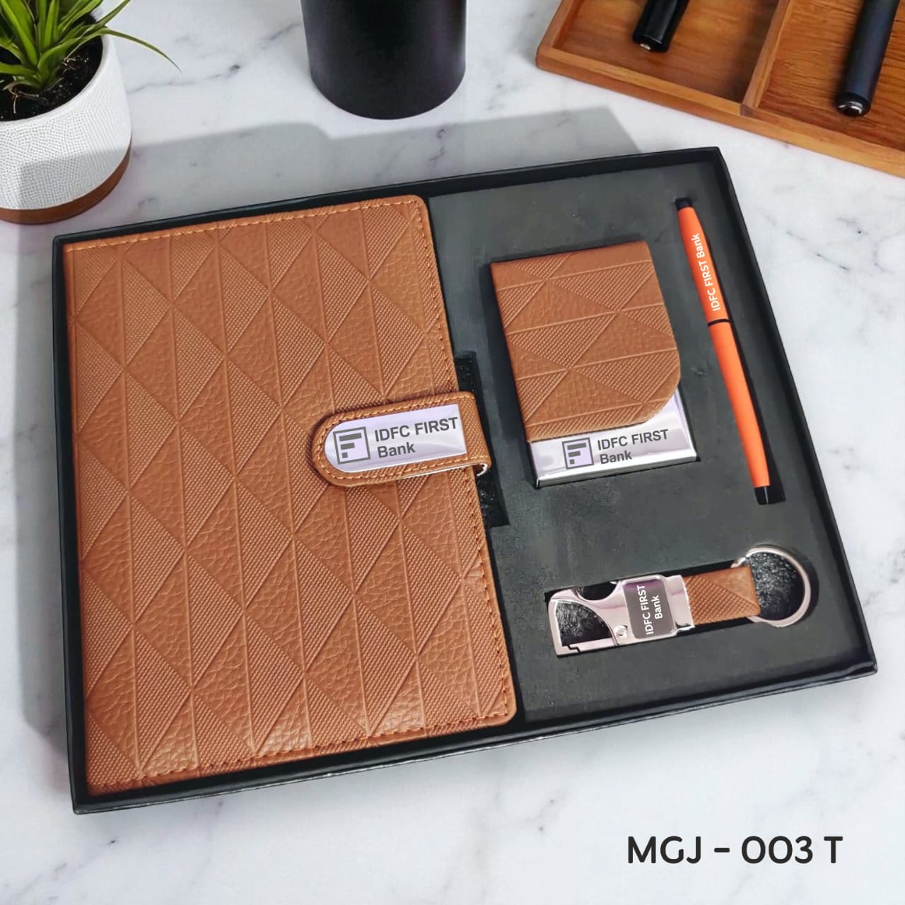 Gift set with brown textured notebook, cardholder, pen, and USB drive on a marble surface.