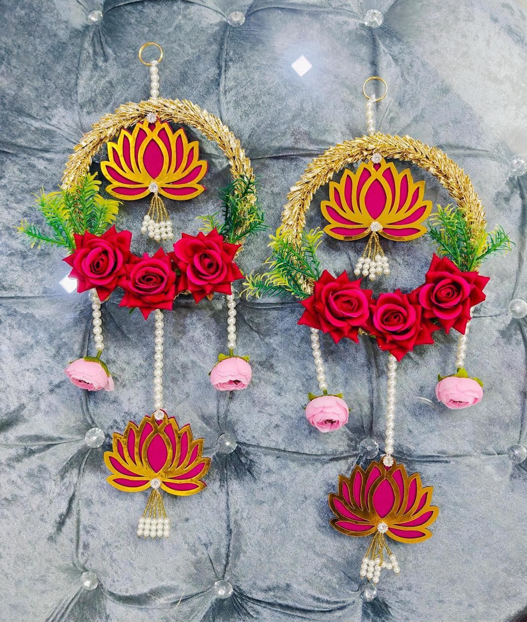 Decorative earrings with pink flowers and lotus designs on a gray textured background