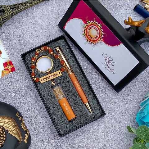 Brother gift combo in box there is one customized orange bpen and cutkey chain highquality rudraksh rakhi with name, beside box cap is there where greeting are written on it 