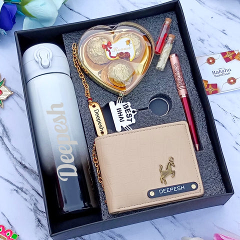 in a black box there one custom flask , chain with brass base on top custom name,heart shape chocolate box,red zari pen,wallet with custom charm and name, 2 small bottles with chawal and roli one greeting card
