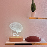 A decorative lamp featuring a detailed wireframe illustration of a human brain, illuminated from a wooden base. The lamp is labeled with the custom title "PSYCHOLOGIST" and the  custom name. 