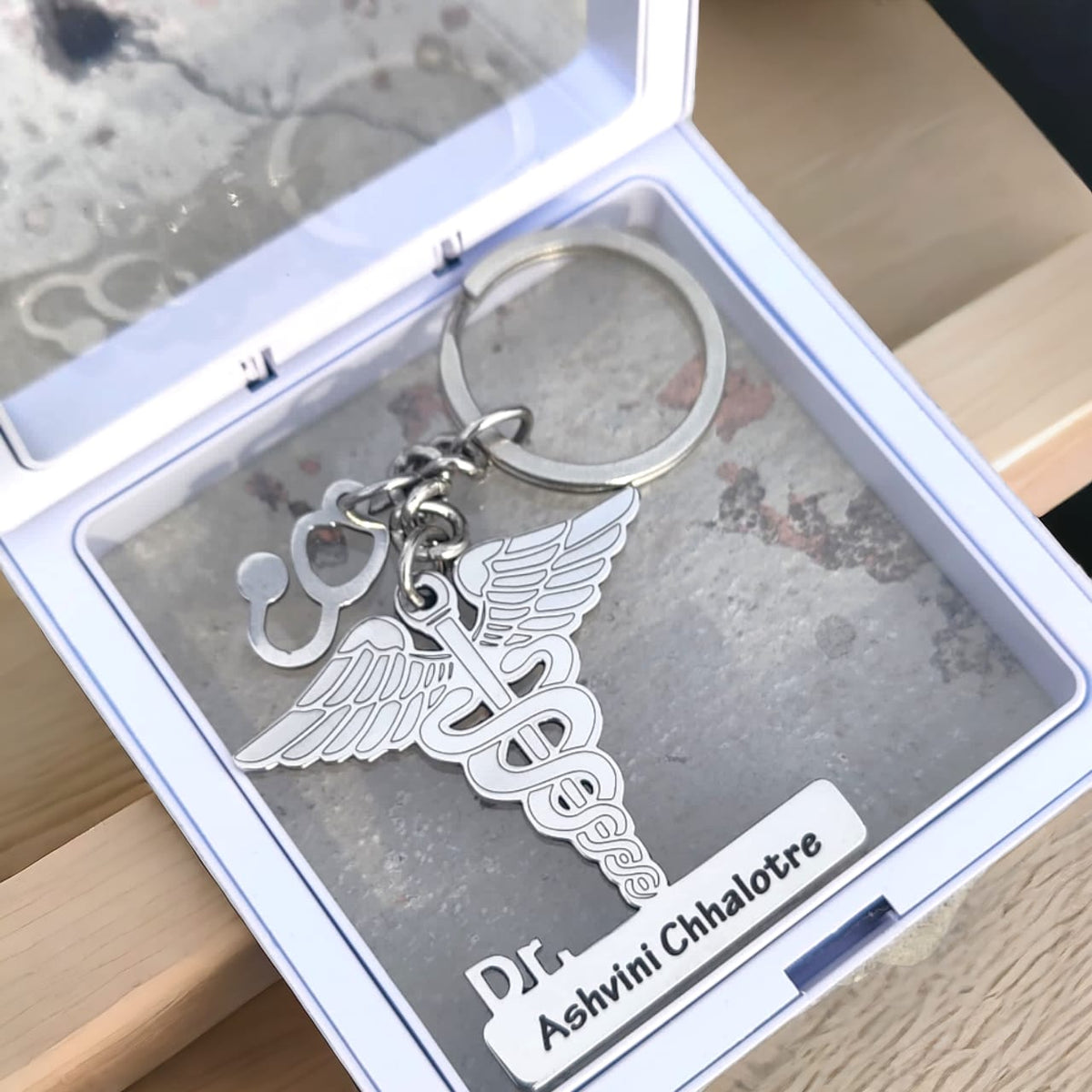 Doctor keychain maed in silver color with doctor logo with custom name place in transparent white box.