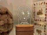 Customizable LED night light featuring a geometric illustration of a human head, personalized with the name to customized and designation displayed on a wooden base in a dimly lit setting