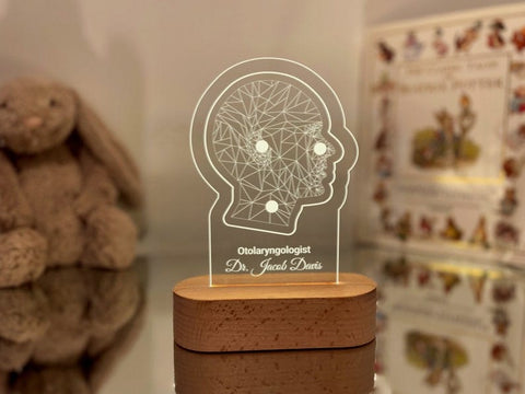 Customizable LED night light featuring a geometric illustration of a human head, personalized with the name to customized and designation displayed on a wooden base in a dimly lit setting