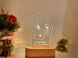 Customizable LED night light featuring a geometric illustration of a human head, personalized with the name to customized and designation displayed on a wooden base in a dimly lit setting