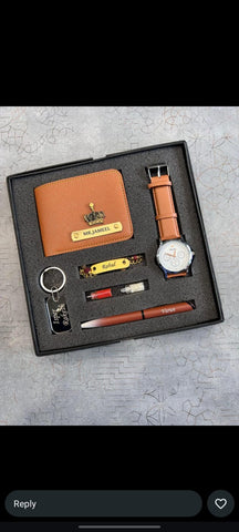 A men's gift set in a black presentation box, featuring a brown leather wallet, matching watch strap, wristwatch, pen, keychain, and a small yellow accessory on a gray textured background.