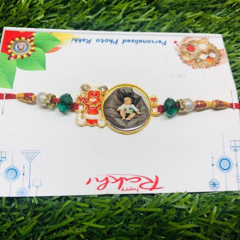 mental rakhi with customized with photo and teddy sticker beside the photo ,on red thread green and white beed are there,