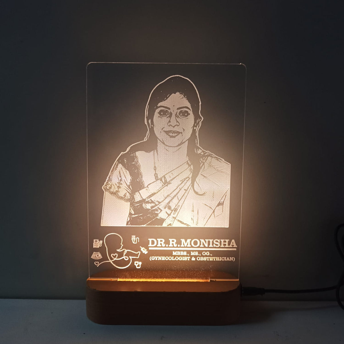 Lamp with engraved portrait and name on a dark background