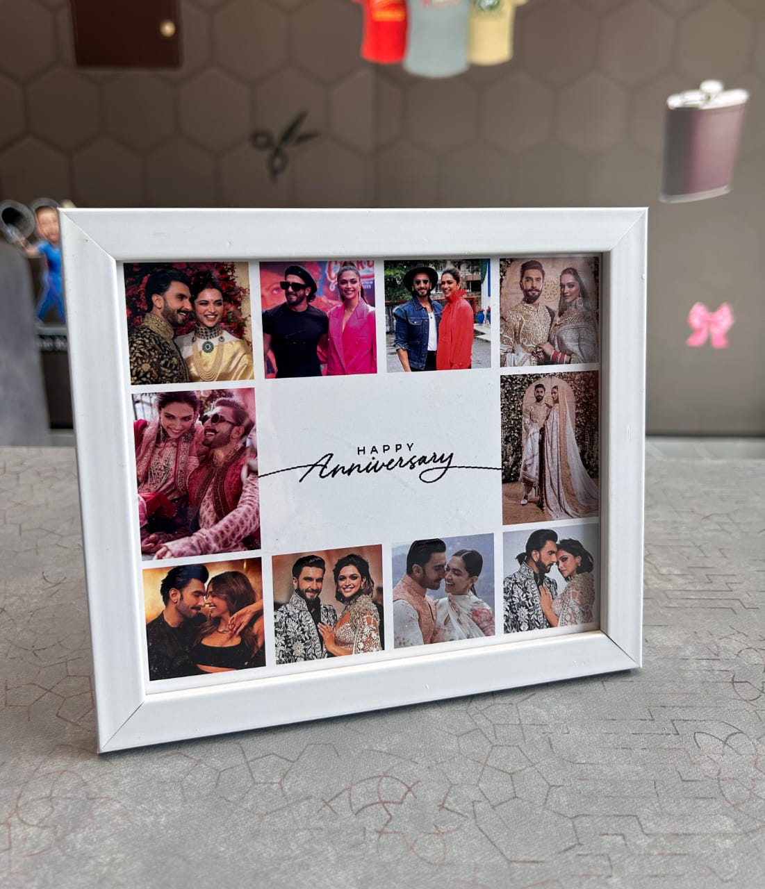 White photo frame with multiple cut-out pictures of a couple, placed on a textured surface.