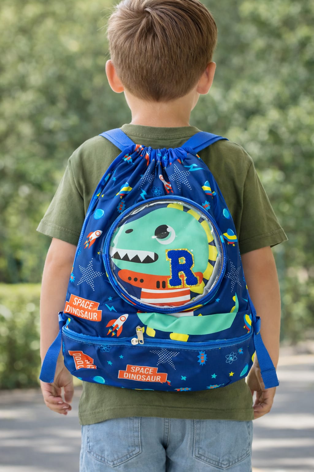 Child wearing a blue backpack with a dinosaur design outdoors