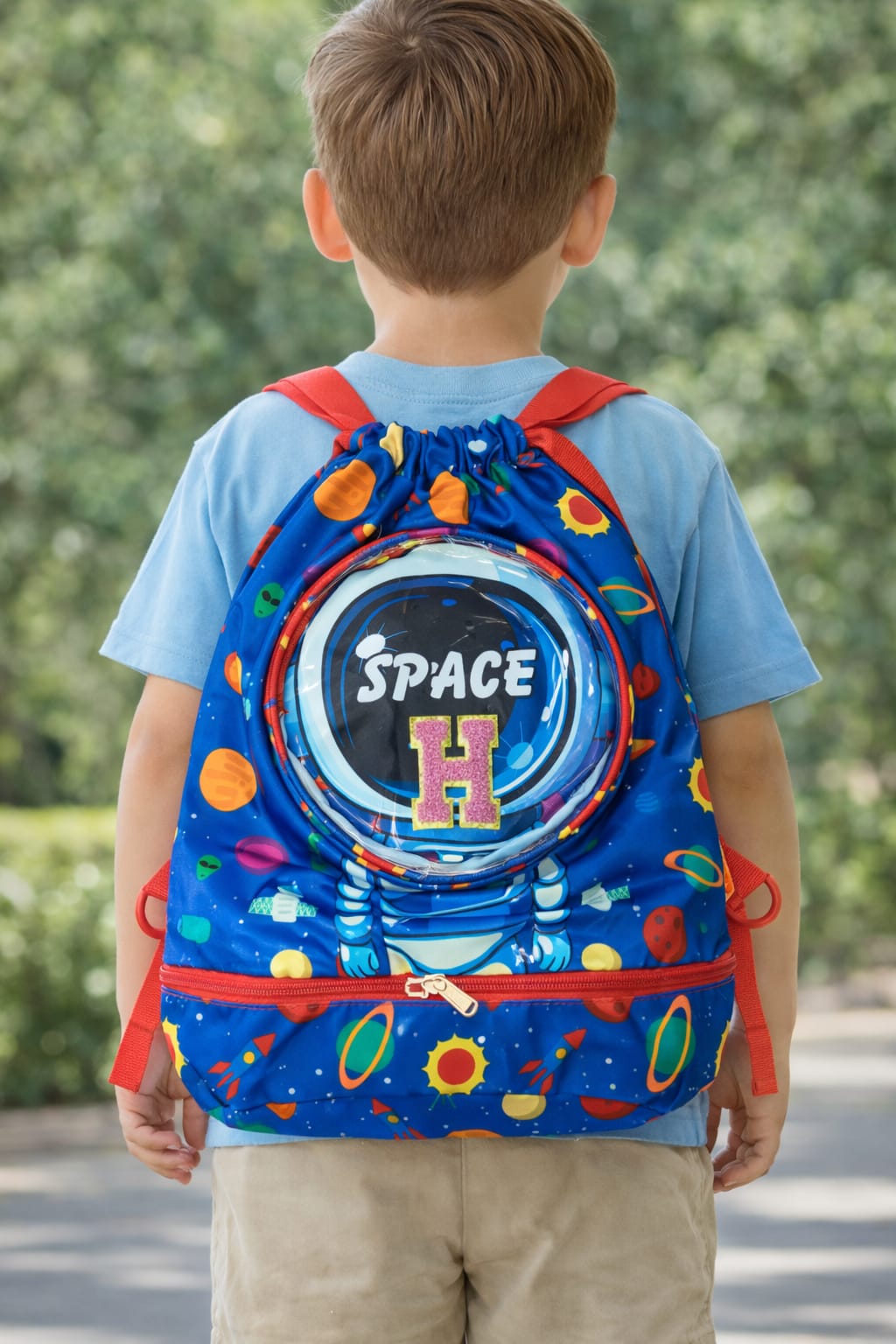 Child wearing a colorful backpack with 'Space' design outdoors
