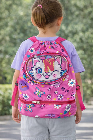 Child wearing a pink backpack with a cartoon cat design outdoors.