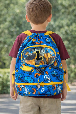 Child wearing a blue backpack with construction vehicle pattern outdoors