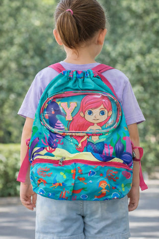 Child wearing a colorful backpack with a mermaid design outdoors.