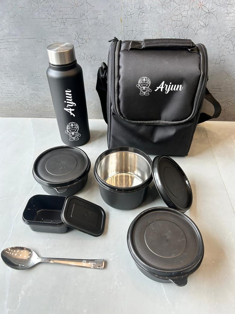 Black meal prep containers, water bottle, and bag with 'Arjun' branding on a light surface.