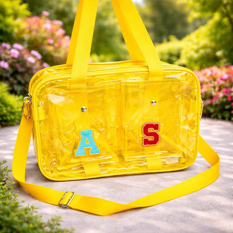 Yellow transparent handbag with 'A' and 'S' letters on a blurred natural background