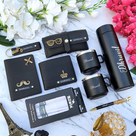 Collection of black accessories with 'Dhruvil' branding on a marble surface with flowers.