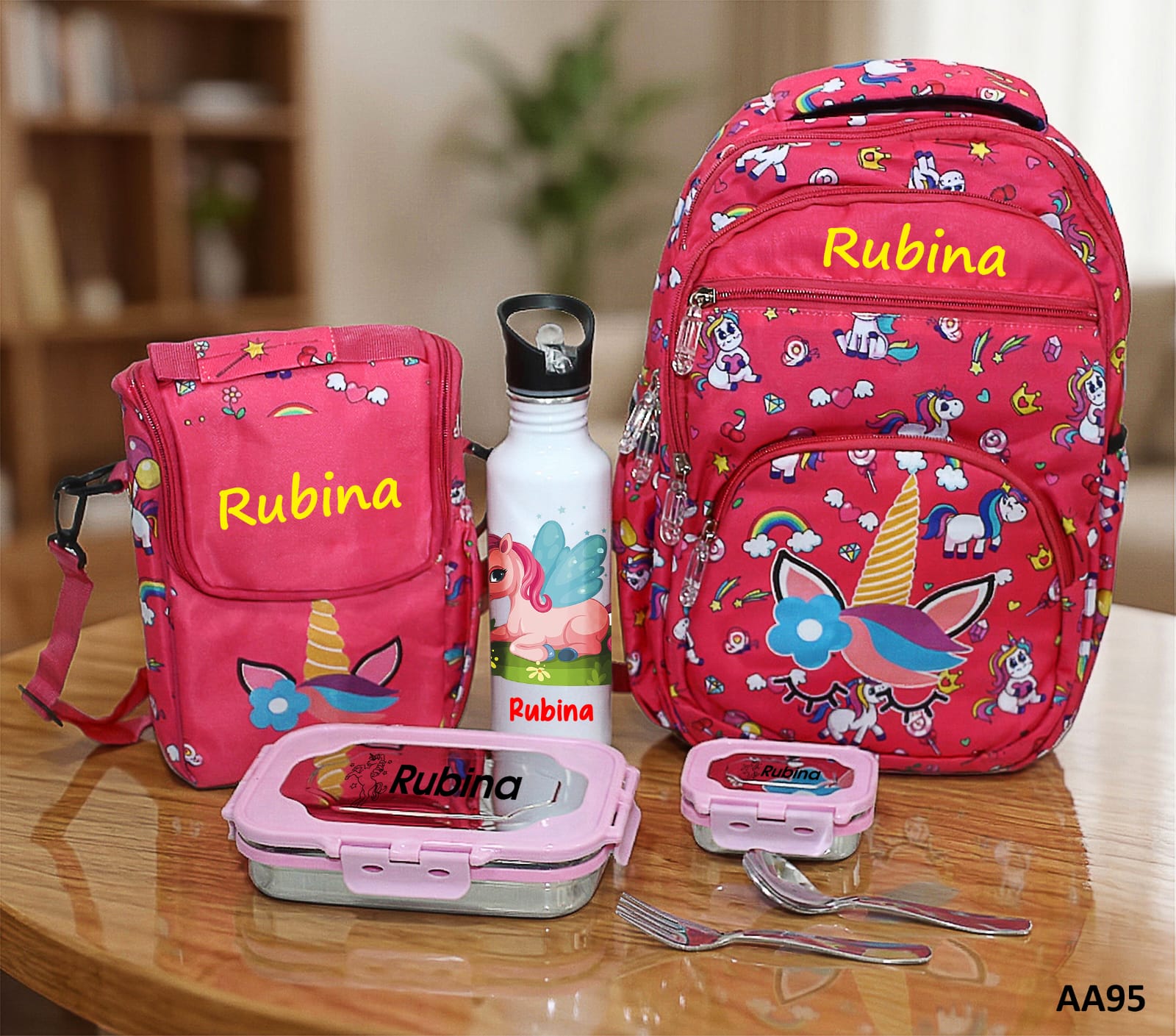 Pink backpack with unicorn design and matching lunch box, water bottle, and containers on a wooden table.