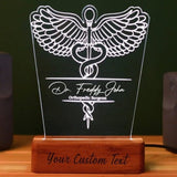 Customizable LED night light featuring a detailed caduceus symbol, personalized with the personalized name   and the any customized designation displayed on a wooden base with the option to add custom text at the bottom